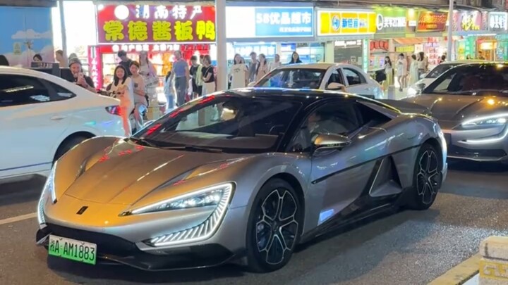 The仰望U9 takes off mid-jump right in the bustling city center—two girls on an electric scooter are le