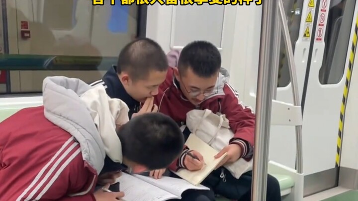 三位男生在地铁里研究作业，这造型一看就是学霸……