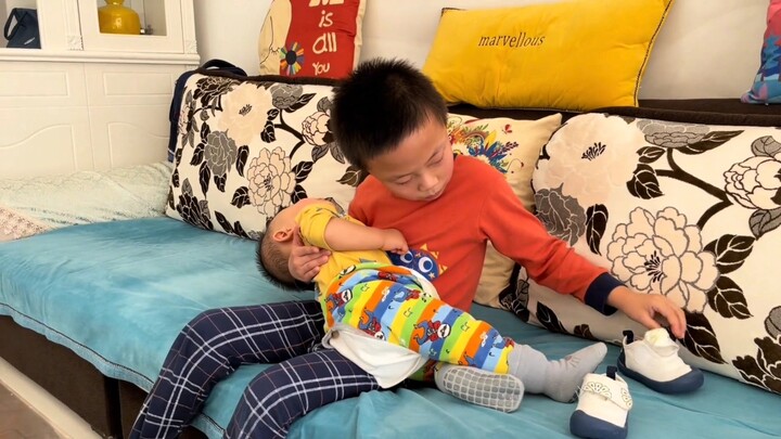 In front of the older brother putting the baby to sleep, even dad is like a little brother—unable to