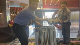 Seorang penjual yang lahir pada tahun 2000-an memperkenalkan sebuah rumah kepada seorang pelanggan. 