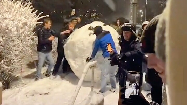 学生们把巨大的雪球推下台阶