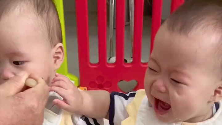 One child is coaxed to eat, while two children are vying for it.