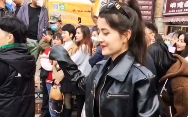 The young lady at the Xinjiang bazaar dances gracefully with a sweet smile—the pinnacle of street da