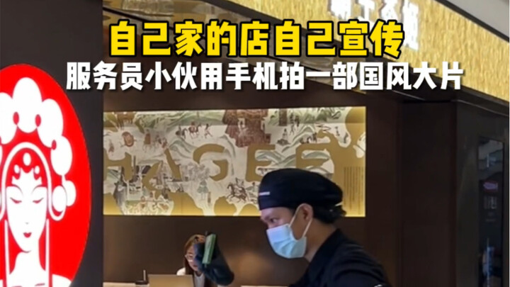 服务员小伙拿手机给自己的店拍宣传片