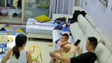 The baby fell from the sofa, and the father who was playing with his mobile phone caught him with hi