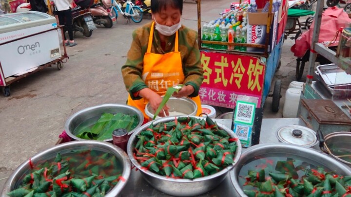 At a roadside stall in Gushi, Henan, Thai jasmine rice zongzi are sold for just RMB 1 each. The aunt