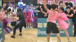 The boy didn't want to dance with the girl but was dragged to the stage by the teacher. The music am