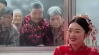 新娘坐在婚床笑开了怀 老人们隔着窗户围观