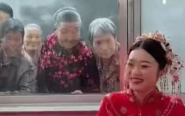 新娘坐在婚床笑开了怀 老人们隔着窗户围观