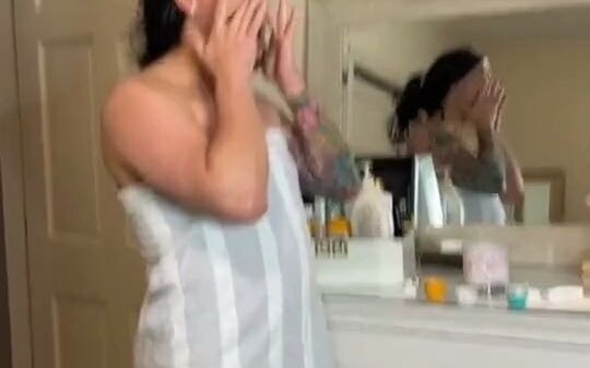 The man imitates his wife who just took a shower, and the posture of applying body lotion is very sk