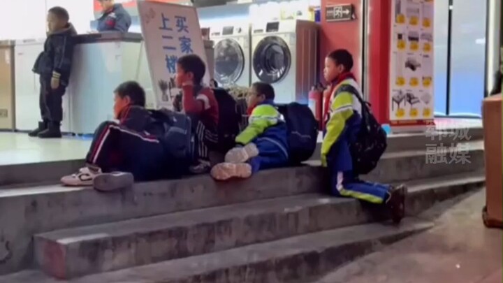 Children's happiness is so simple. A group of primary school students are watching TV in front of th