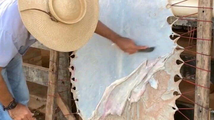 Why is raw cowhide stretched tight before fat is shaved off?