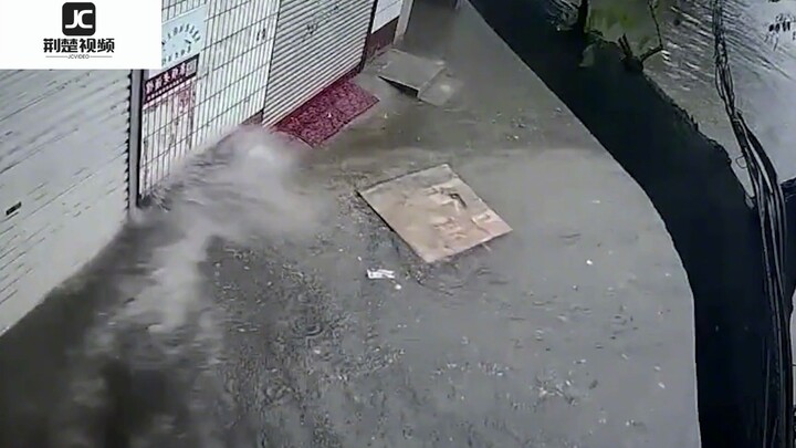 ฝนตกหนักทำให้ถนนน้ำท่วมขัง รถวิ่งผ่านน้ำจนเกือบไหลเข้าบ้าน ชายคนหนึ่งคว้าจับได้ทันและดึงประตูม้วนลงม