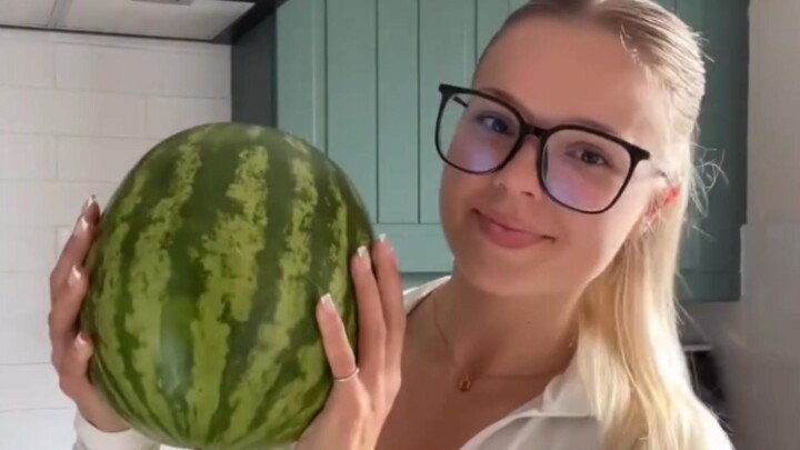 Young lady squashes a watermelon with her thighs.