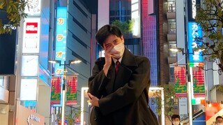 Seorang pria berjaket menari mengikuti lagu baru ITZY CHESHIRE di jalanan Shinjuku