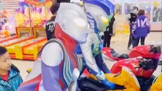 Ultraman rides a motorcycle in an amu*t park.