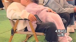 小女孩主动找小孩哥玩，小孩哥一手拿玩具枪一手抱着小女孩