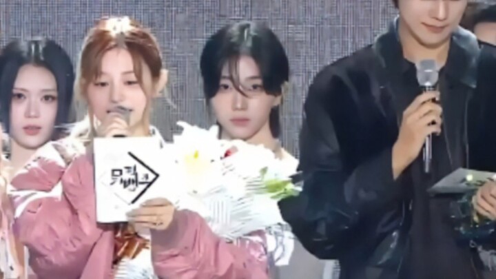 Hot Topic on Korean Social Media: Which male idol, standing behind the music show MC, looks like a g