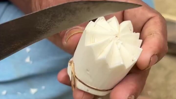 An Indian is teaching you how to make a flower out of pith paper.