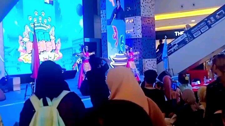 Panggung pertunjukan busana tradisi. Di belakang panggung,tampak dalang memasukkan tangannya kedalam