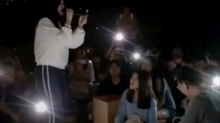 A man and a woman sing "All Is Love" on the university playground