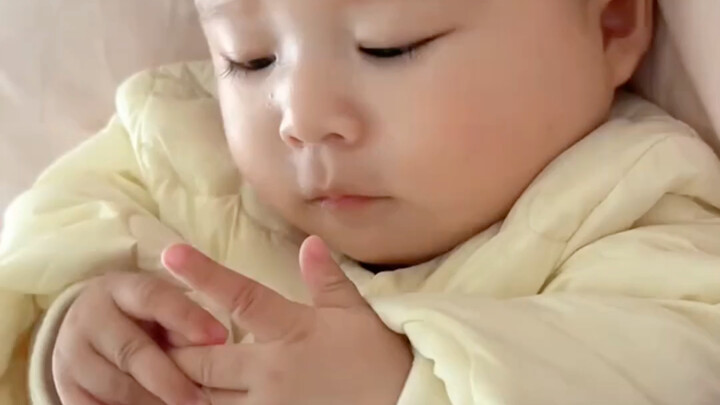 A little baby whose hands are nervously fidgeting because they got scolded for not eating properly!