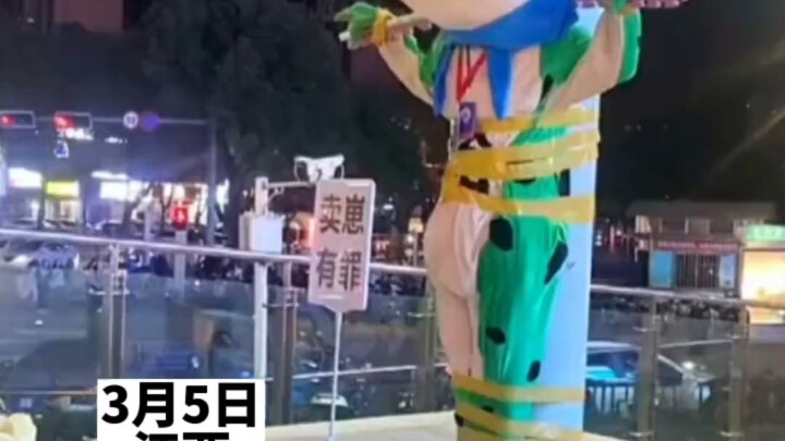 دمية الضفدع مربوطة بعمود كهرباء، وأمامها لافتة تقول: "بيع الصغار إثم."