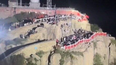 Tourists on a nighttime climb of Mount Tai shine flashlights at each other.