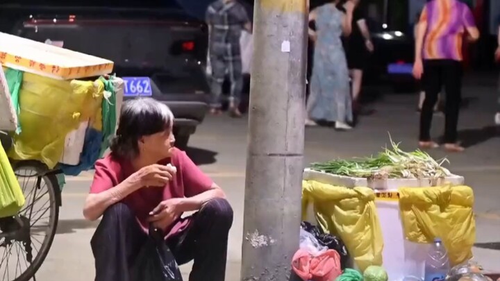 Two sides of life captured in a single shot: Up close, a mother-in-law watches over unsold vegetable