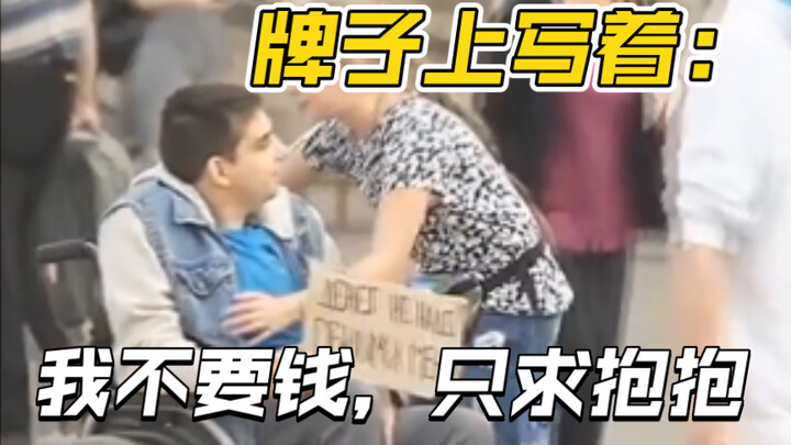 The sign reads: “I don’t want money, just a hug.”