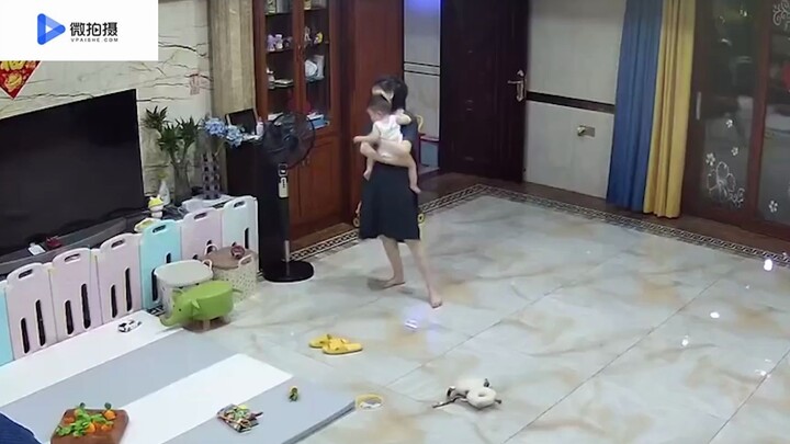 Mom dances gracefully with baby in her arms right after work, while Dad watches the monitor and laug