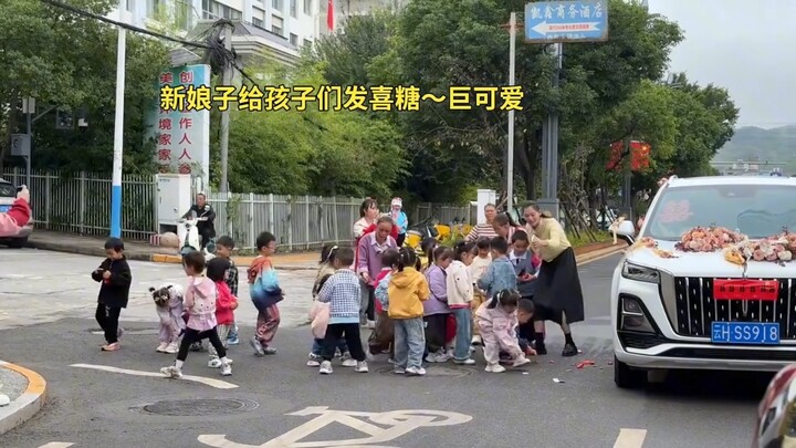 Kindergarten kids spot a wedding car on the street, and the bride hands out wedding candies to the c