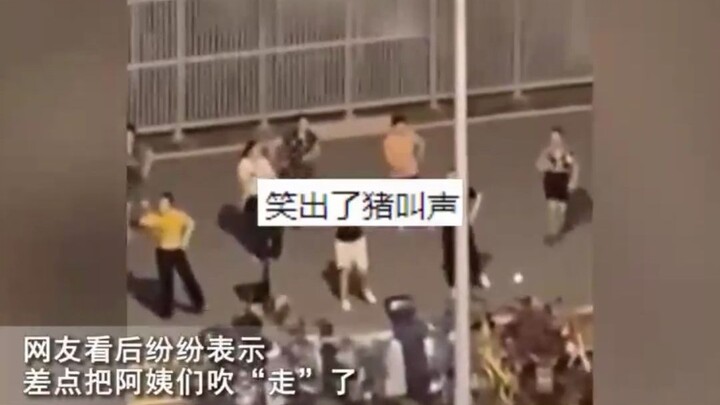 Một bà lão đang nhảy múa trên quảng trường trong khi một người đàn ông đang chơi đàn suona theo điệu