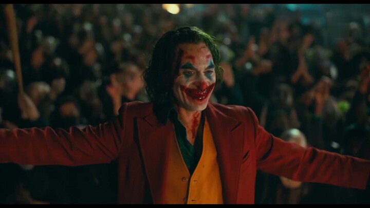 Joker(2019): Arthur paints a smile on his face with blood and the whole city cheers for him (close-u
