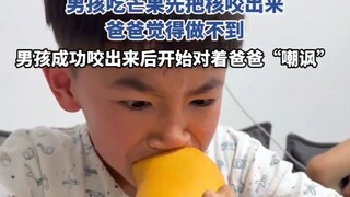 男孩吃芒果先把核咬出来，男孩成功咬出来后开始对着爸爸“嘲讽”