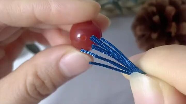 How do you thread multiple strands of cord through a small-hole bead?