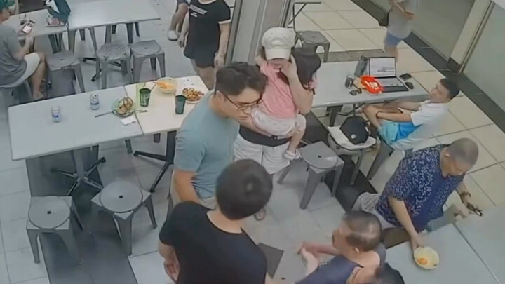 A 70-year-old man who appears to have a walking disability pats a little girl on the head at a resta