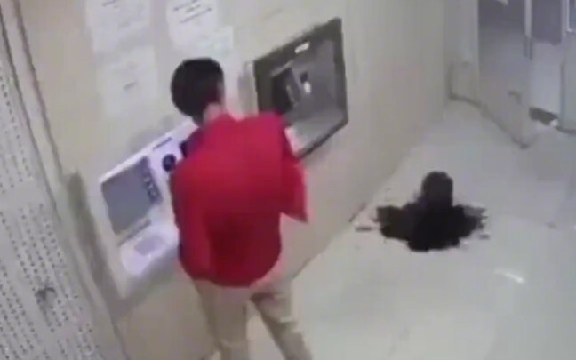 فجأةً، انبعث سائل غريب أسود كالحبر من الأرض تحت ماكينة الصراف الآلي، ففُزِع الرجلُ ثم تابع سحبَ الما