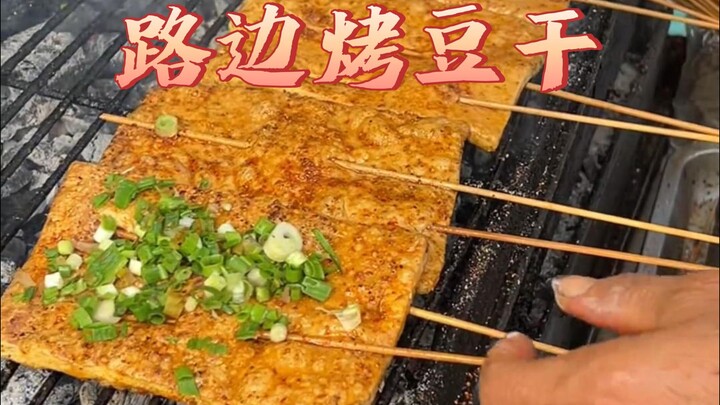 A barbecue stall outside a convenience store by the roadside, with every plate piled high with dried
