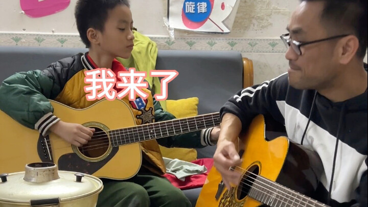 Father and son strum and sing “Gray Trajectory” on guitars while enjoying hot pot