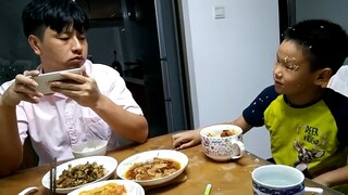 父亲一直玩手机不吃饭，儿子拍桌大怒说快吃饭！