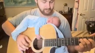 宝宝趴在爸爸的吉他上，听着听着就笑了，好温馨的画面~