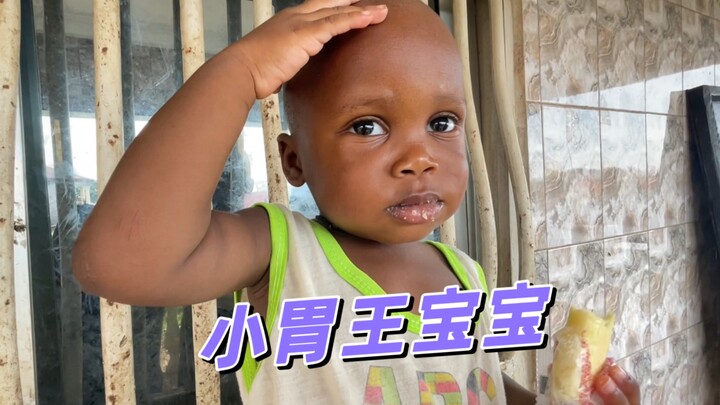 Cute African baby, little glutton—so adorable when wiping the bib with tiny hands!