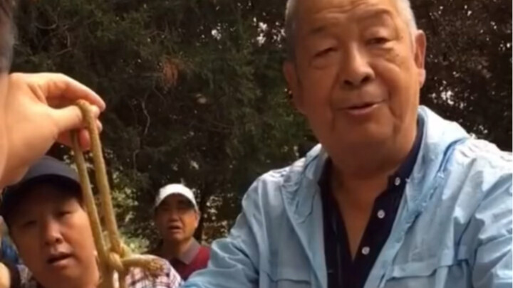Street vendor tricks an older woman with a rope-transcending magic trick!