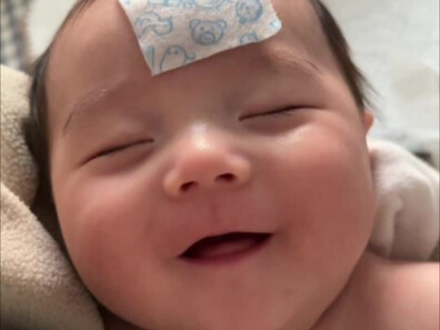 The feverish baby is still smiling while sleeping in mom’s arms—my heart is melting!