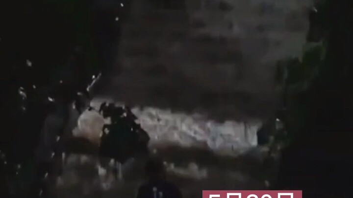 Seorang siswa laki-laki membantu teman sekelasnya membawa makanan di tengah hujan lebat; hujan turun