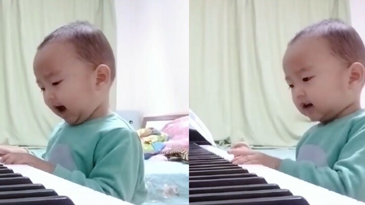 A two-and-a-half-year-old toddler finds the right notes and plays "Hou Lai," singing along while pla