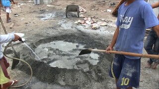 FILIPINO WORKERS PUTTING SAND IN BAGS MIXING CEMENT IN THE PHILIPPINES