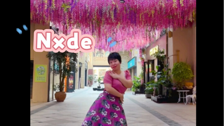 Nxde dances under the wisteria flowers