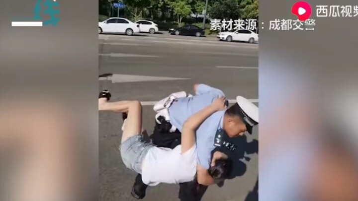 Woman obstructs law enforcement and is taken down with a bear hug by a traffic cop.